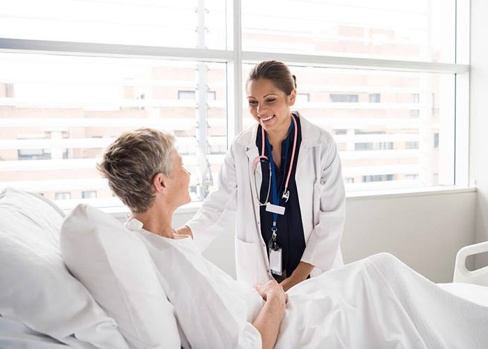 doctor assisting female patient in hospital bed