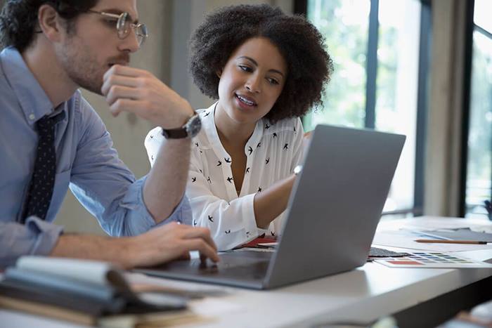 Colleagues collaborating together in front of laptop