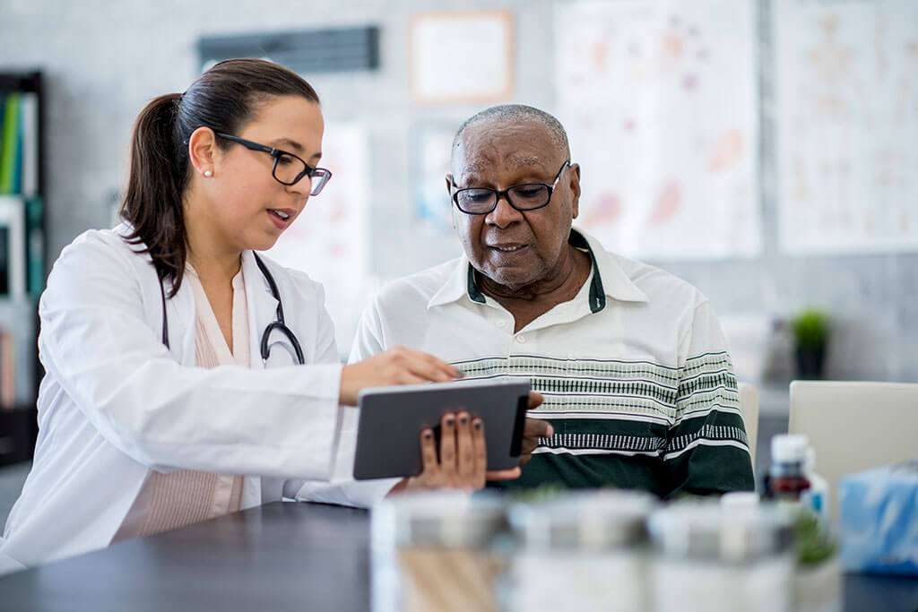 Female doctor showing male patient information on tablet